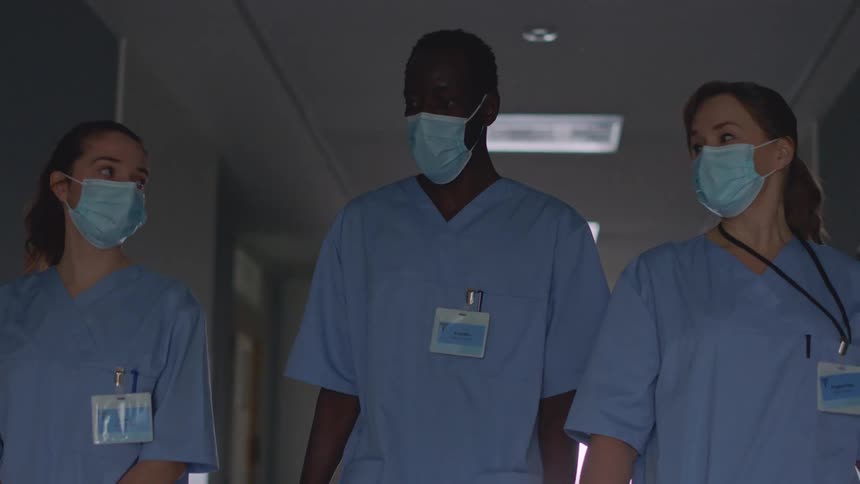 Three nurses walk down a hall in the hospital