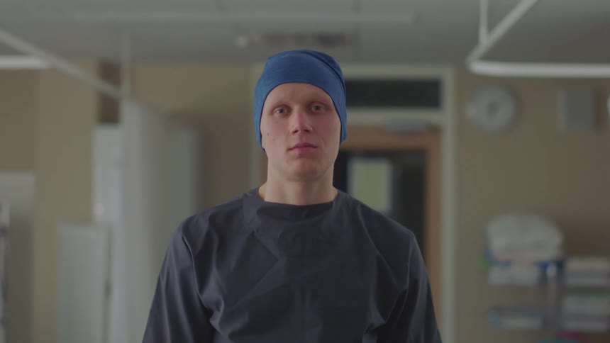 A doctor stands in a hospital in scrubs