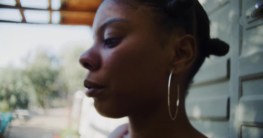 Young woman braiding the hair of a person sitting in the front yard at home in the morning