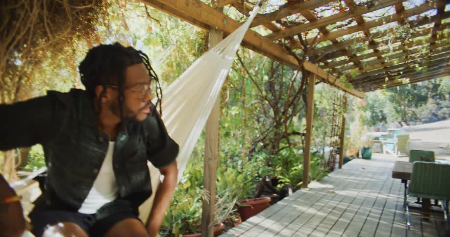 A man gets out of a hammock tied to his porch