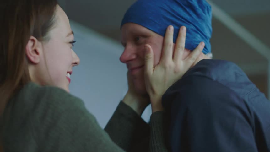 A hospital patient hugs his wife and his doctor after receiving good news