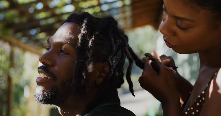 Woman listens and plaits mans hair as he talks