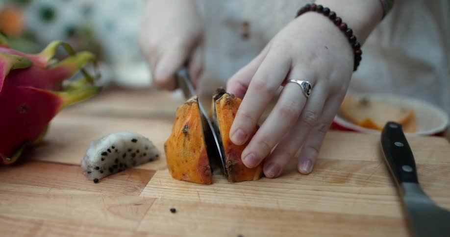 A woman slices a papaya in half