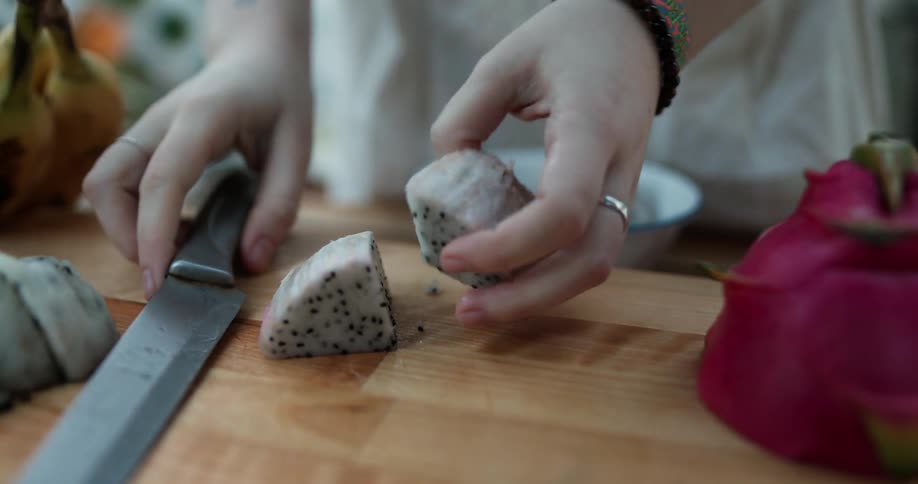 Woman slices peeled dragon fruit
