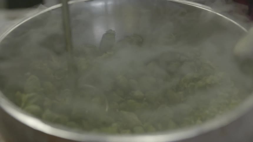 Person turns pot while pushing food underwater with ladle