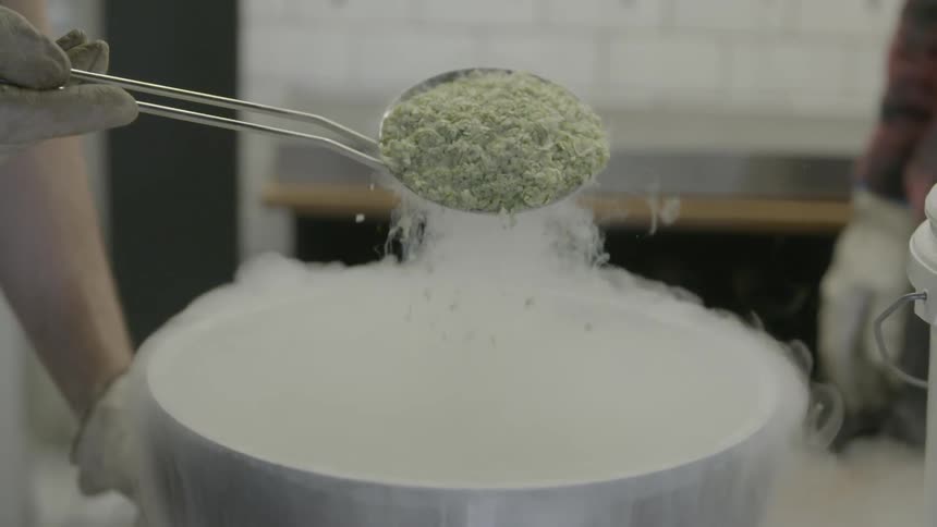 Food is being ladled into a metal pot that is smoking