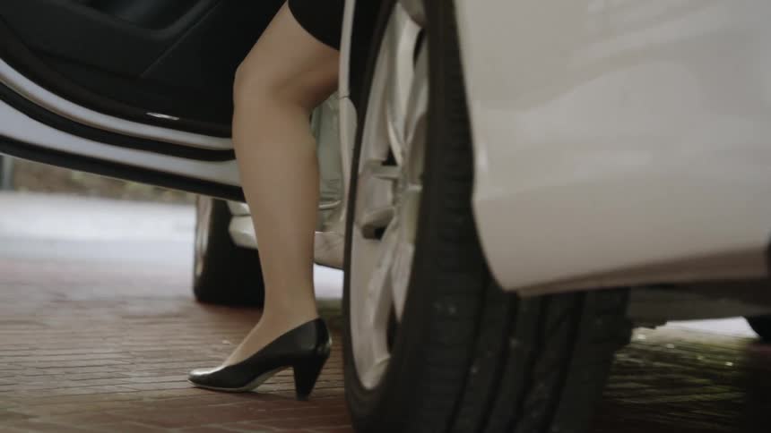 A woman slowly gets out of a car