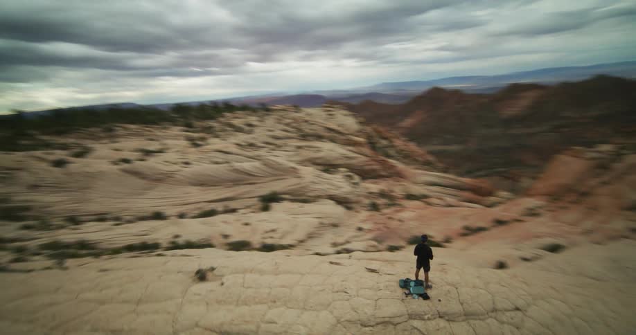 Person stands on stony mountain looking over badlands