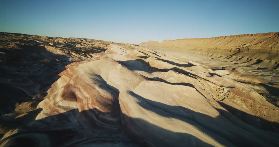 Small peaks along throughout the valley of a canyon cast shadows on the ground