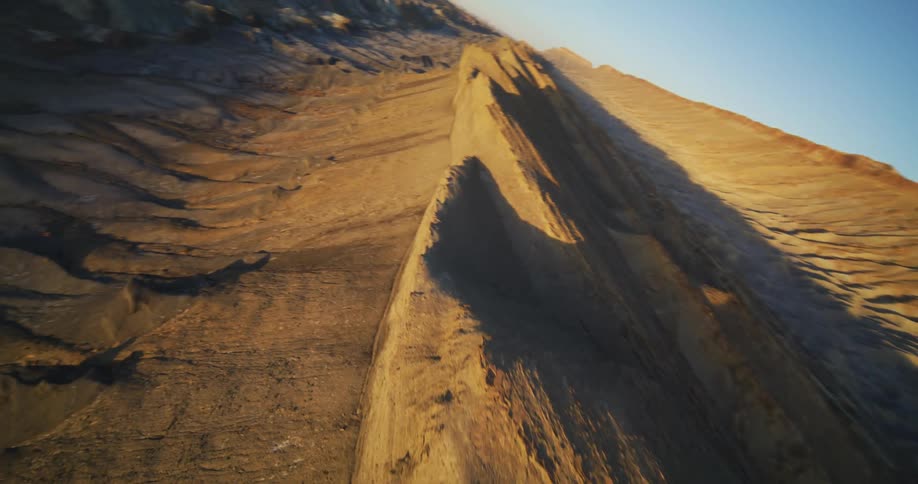 The sun shines brightly on a mountain ridge and shadows fall on the canyon below