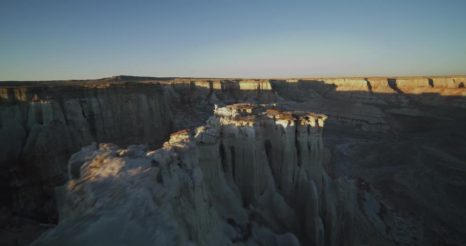 A van carrying camping equipment drives close to the edge of a narrow canyon peak