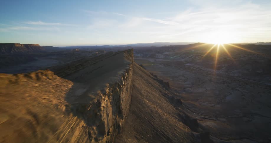 The sun shines brightly on a mountain ridge as it sets on the horizon