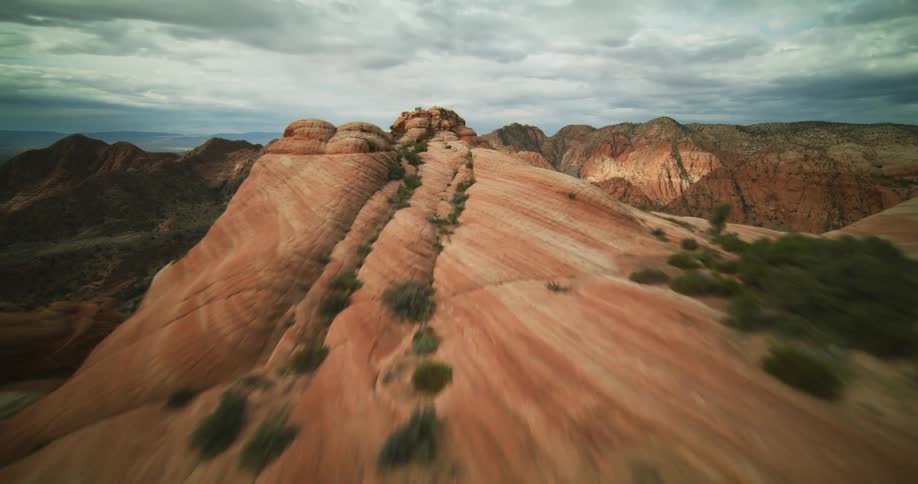 Aerial view moving over badlands mountains and canyons under a cloudy sky