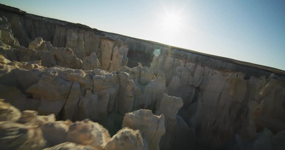 A man hikes along the top of a cliff in a desert canyon