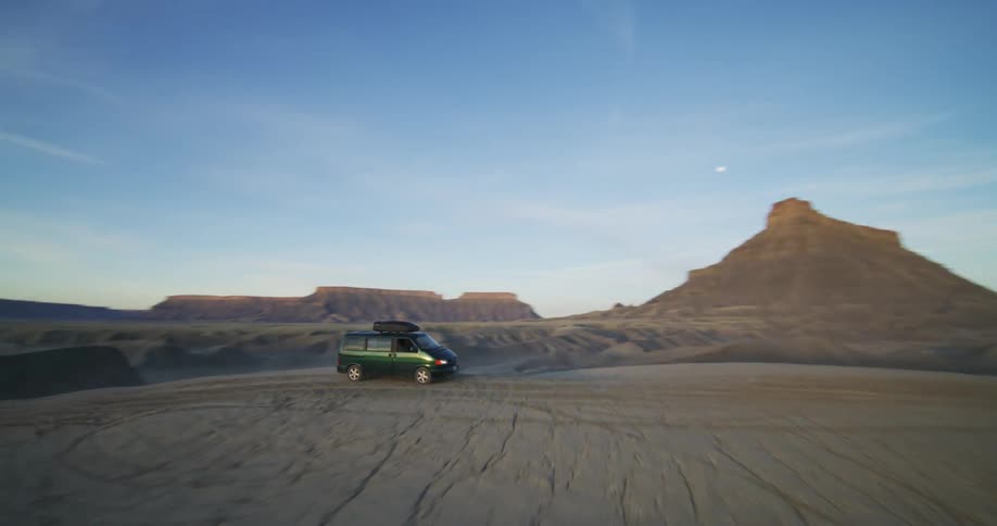 A van with a camper on top leaves the site of a canyon