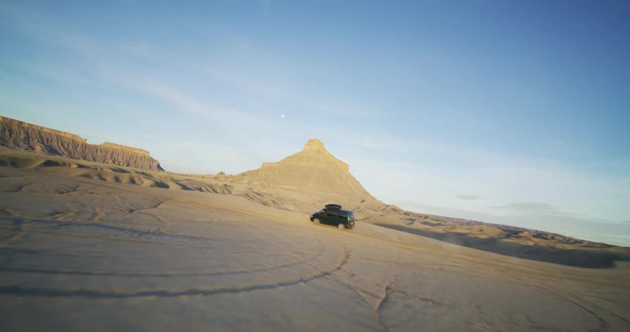 A van drives toward the edge of a cliff in the desert