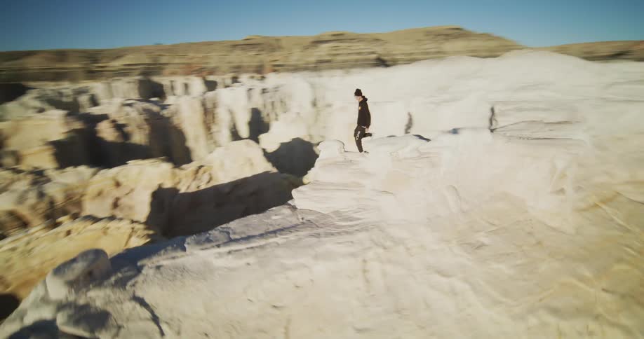 A man is hiking on a tall formation in the desert canyon