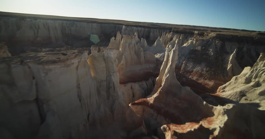 Canyon winds through valley next to plain under a sunny sky