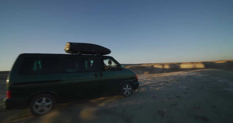 A van travels along the sand near a desert canyon