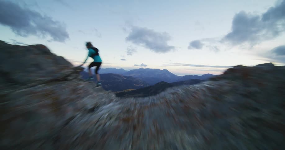 Person quickly crosses ridge overlooking valley with a pond under a red tinted sky