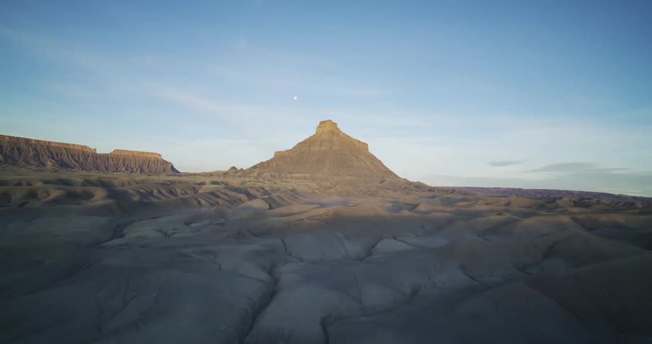 A van climbs up a sand dune in the desert near a tall mountain