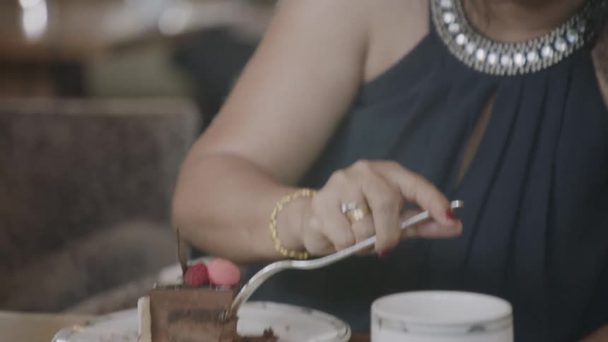 A smiling woman uses her fork on a slice of cake