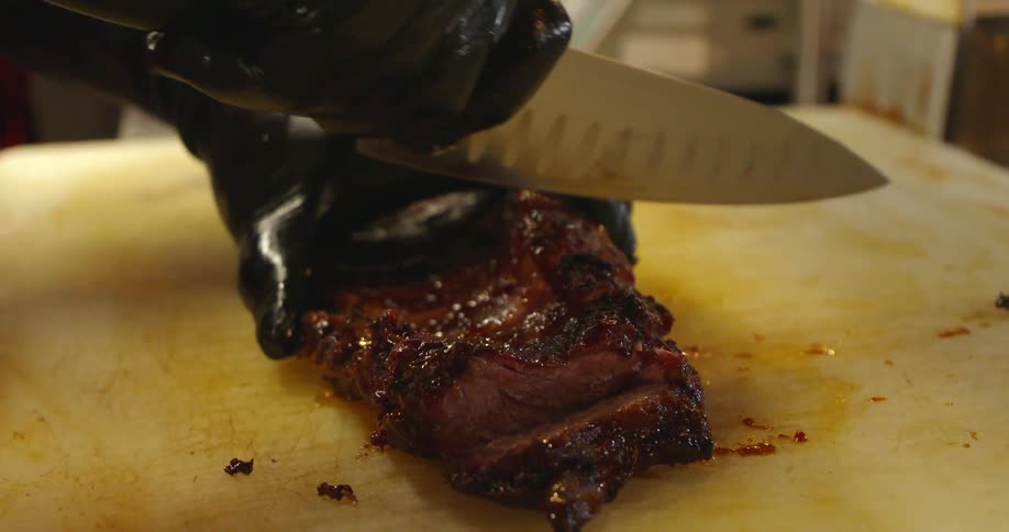 A person is cutting a piece of meat with a knife