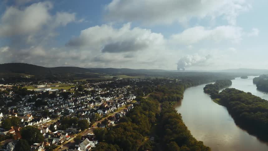 The Susquehanna river forks as it passes a suburban neighborhood. Steam rises from a nuclear power plant in the distance.