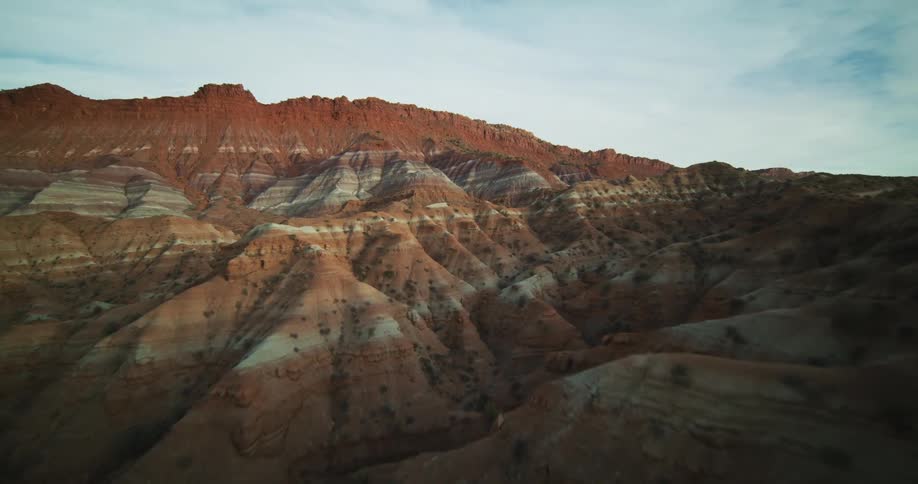 A truck travels on a road through rock formations and mountains in the badlands with a mountain ridge in the distance