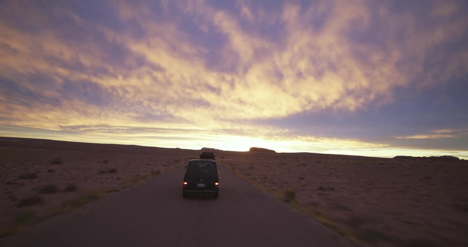 Aerial view of van driving on highway in desert at sunset