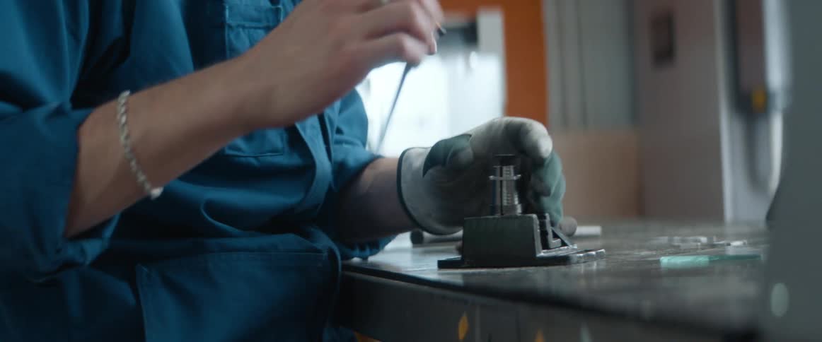 A woman uses an allen wrench to tighten a device in a lab