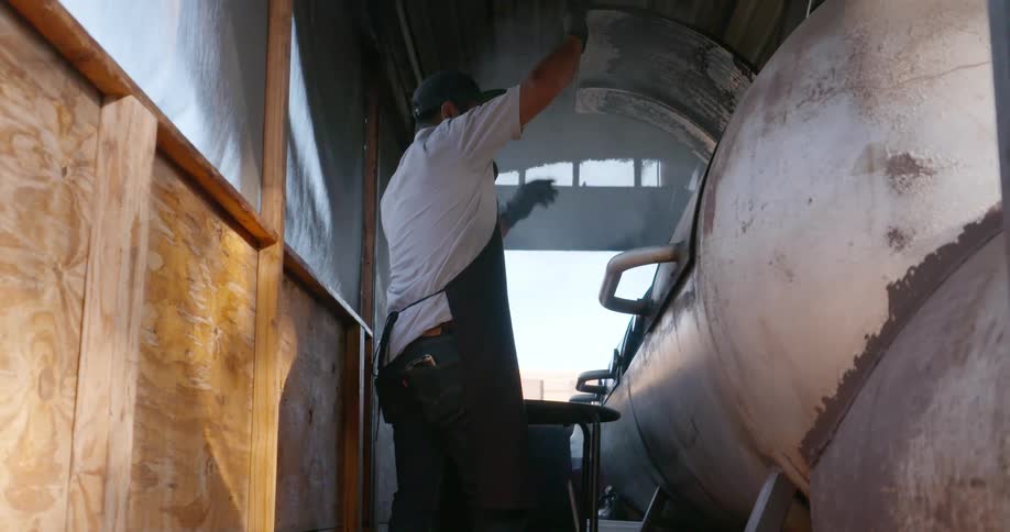 A man opens a smoker grill in a shack