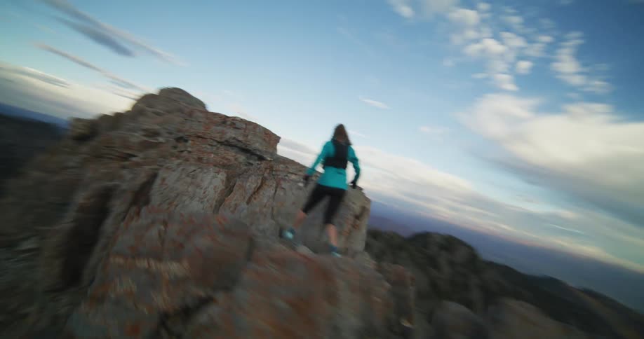 A woman hikes up a tall stone cliff