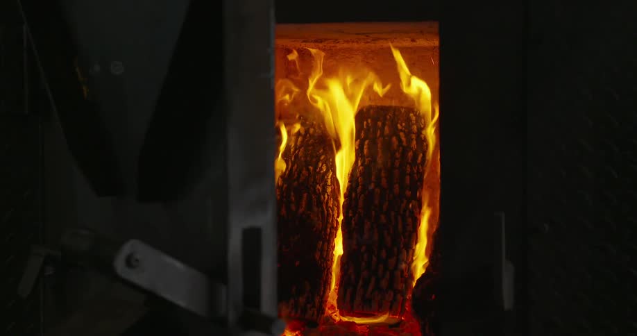 Logs in a furnace are burning as bright flames flicker