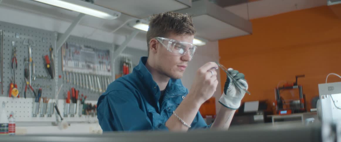 A lab worker closely examines a glass slide as he holds it up and flips it