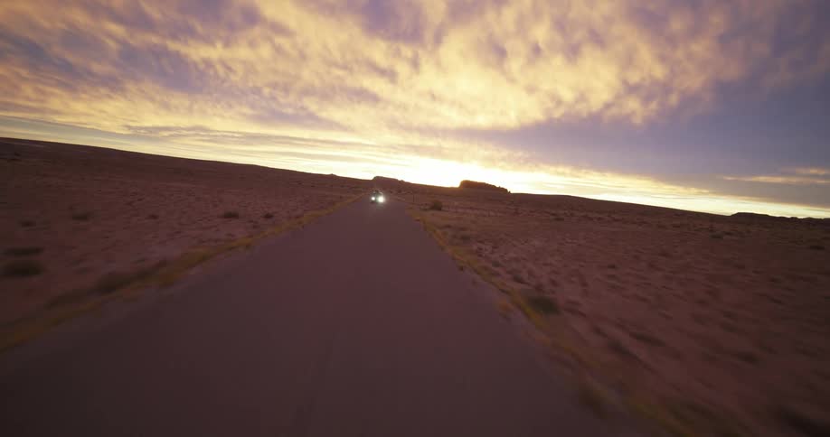 Aerial view of van driving on road in desert at dusk
