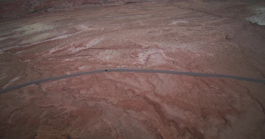 A car is driving on a road in a desert area