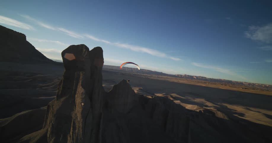 A person paraglides over a desert area
