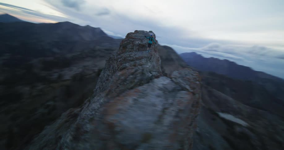 A person is jogging on top of a mountain ledge