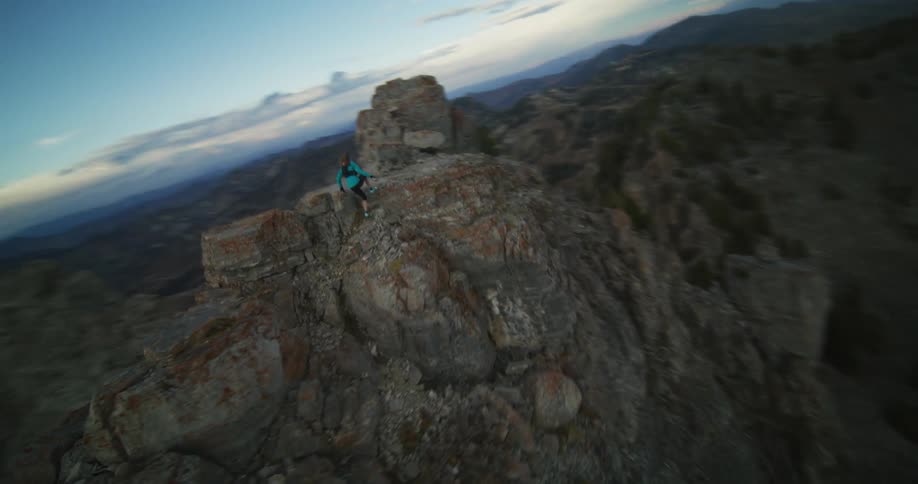 Hiker walks across ridge in mountainous landscape