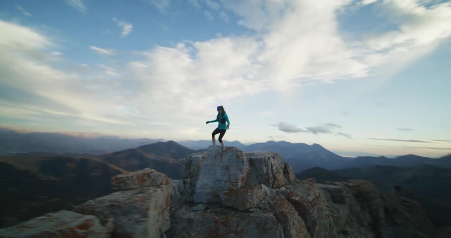 A woman briskly climbs up a stone formation above the canyon