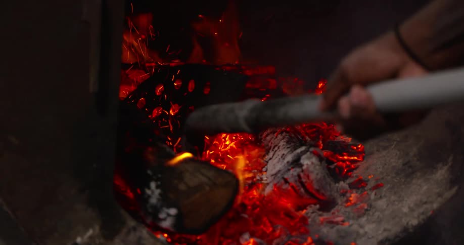 A person stirs coals in a fire