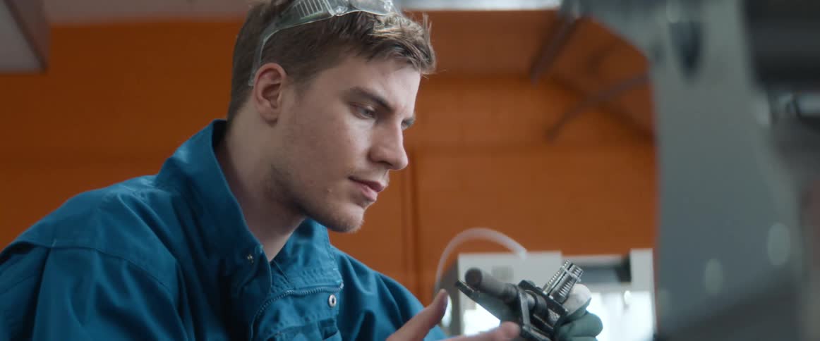 A lab worker lifts his goggles to take a closer look at an object