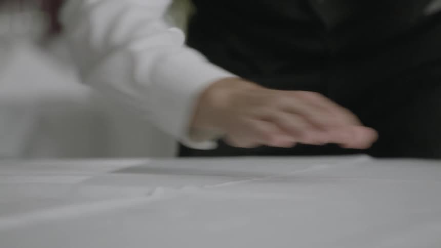 A man wipes a table cloth straight
