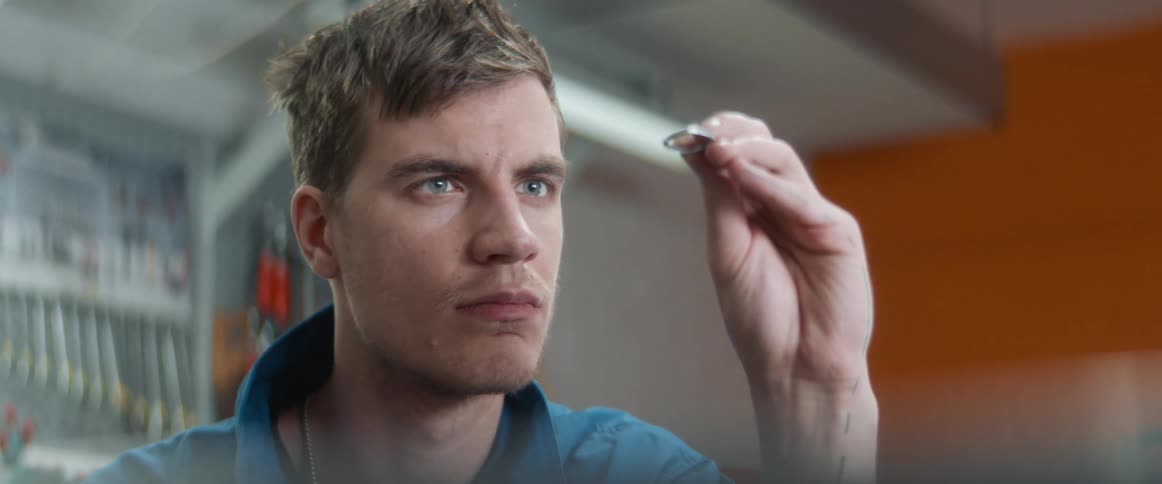 A man examines a metal ring for imperfections inside a workshop