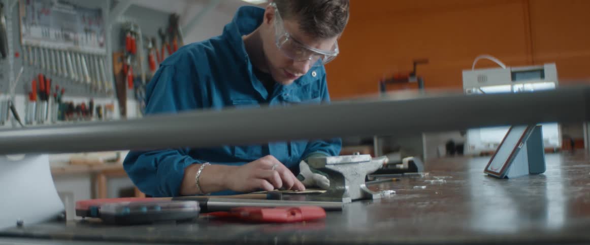 A man saws down an item printed in a three dimensional printer