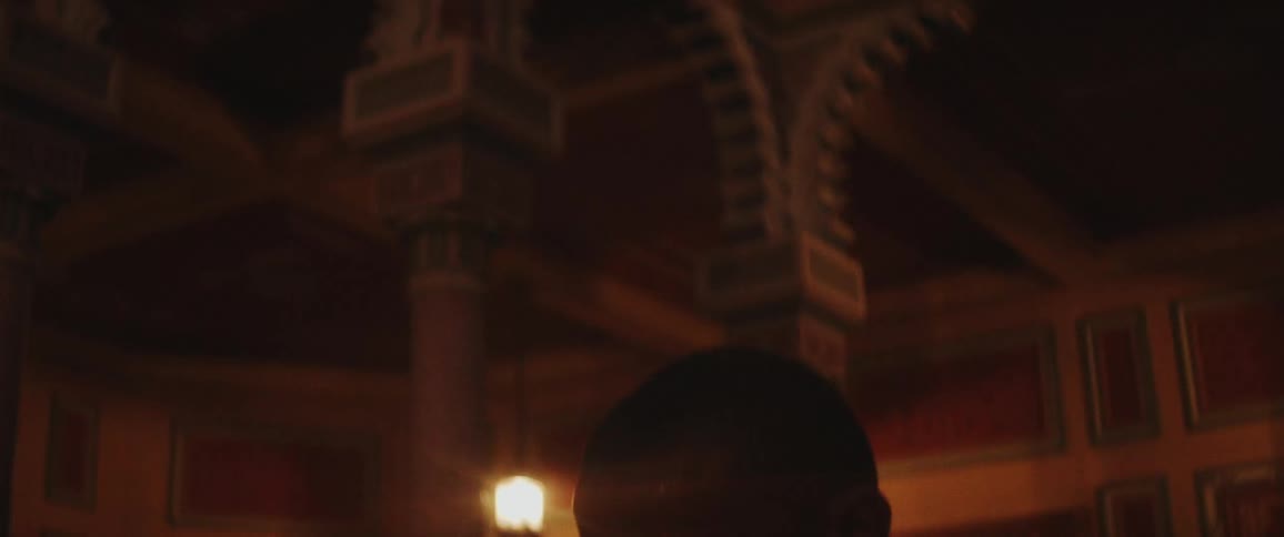 Young man wearing a white shirt crosses with arms crossed over his chest in front of a baroque building at evening