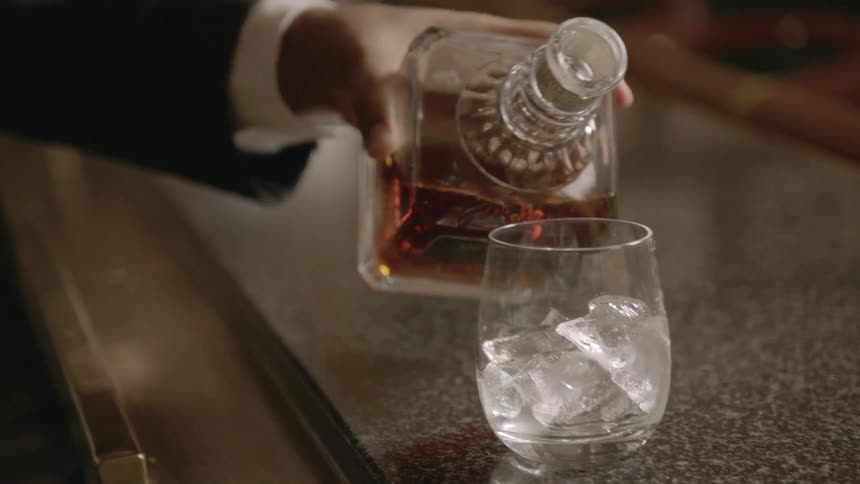 Alcohol is poured into a glass with ice