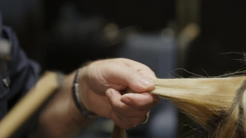 A hairstylist uses a flat iron on a section of hair
