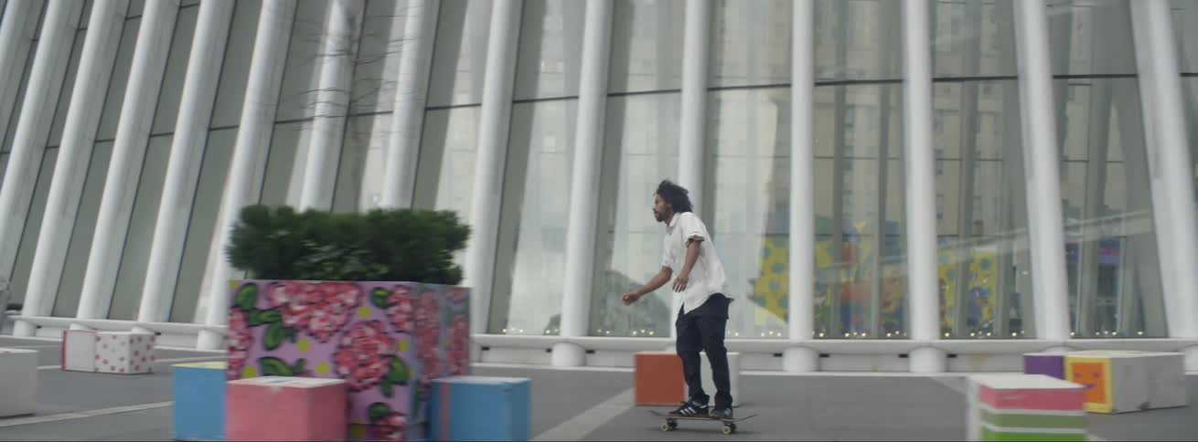 Young bearded man pushing and riding a skateboard on a plaza in the city